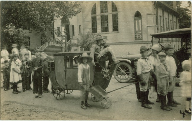 A parade of young people and cars, circa 1925